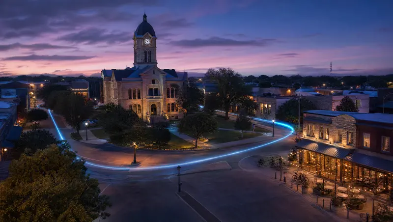 Illustration of a college-town courthouse square with string lights at dusk, representing Denton